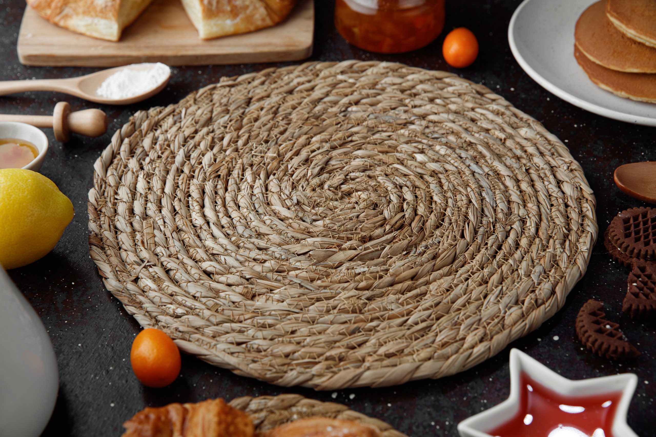 vista-lateral-del-salvamanteles-para-platos-calientes-con-mermelada-de-harina-kumquats-de-limon-croissant-panqueques-galletas-sobre-fondo-negro